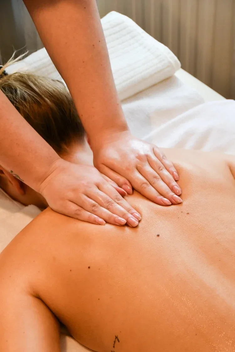 Hands working slowly across a client's shoulders during a massage